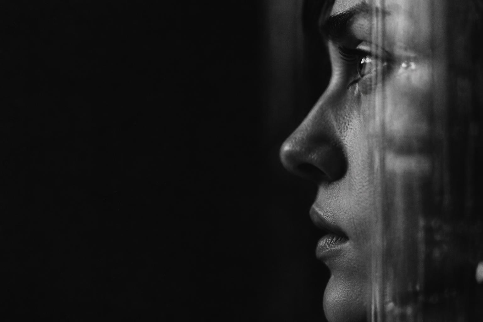 Monochrome close-up of a person seen through reflective glass